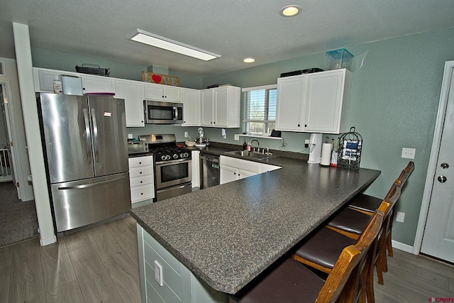 kitchen with stainless steel appliances, white cabinets, and kitchen peninsula