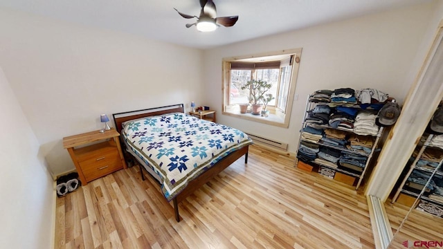 bedroom with ceiling fan, a baseboard radiator, and hardwood / wood-style floors