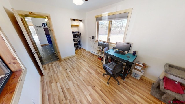 home office with light wood-type flooring and a baseboard heating unit