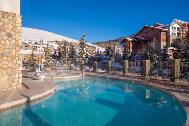 snow covered pool with a mountain view and a hot tub