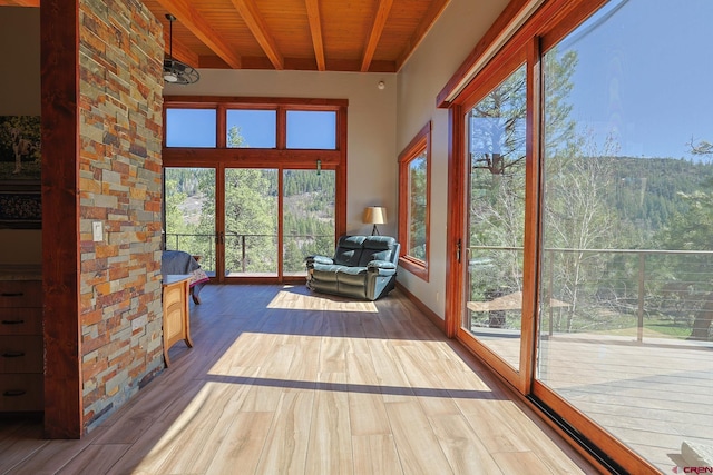 unfurnished sunroom with plenty of natural light, beamed ceiling, and wooden ceiling