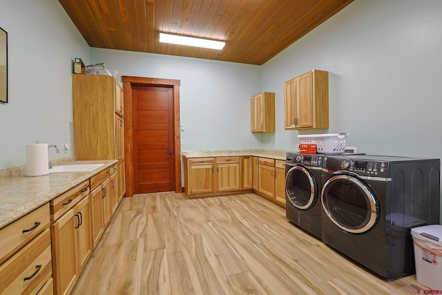 laundry room with wood ceiling, washing machine and clothes dryer, cabinets, light hardwood / wood-style flooring, and sink