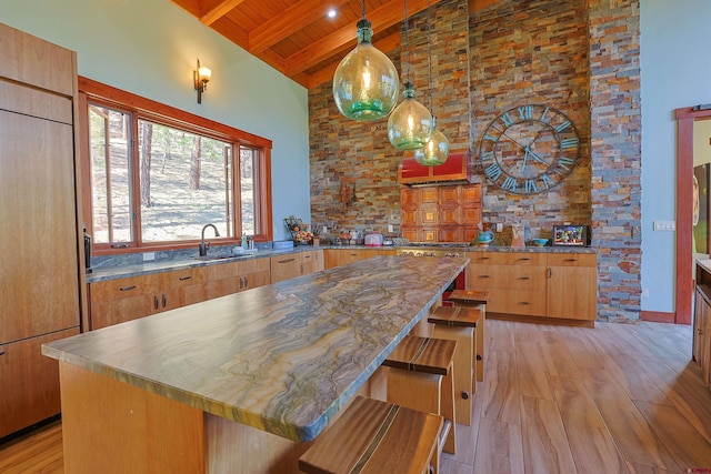 kitchen featuring paneled refrigerator, a center island, beamed ceiling, high vaulted ceiling, and wooden ceiling