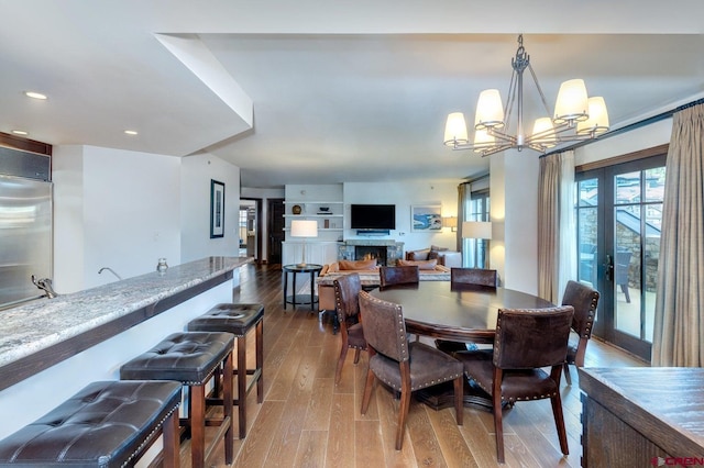 dining area with built in shelves, a chandelier, and light wood-type flooring