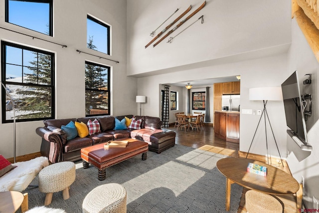 living room with a towering ceiling and dark wood-type flooring