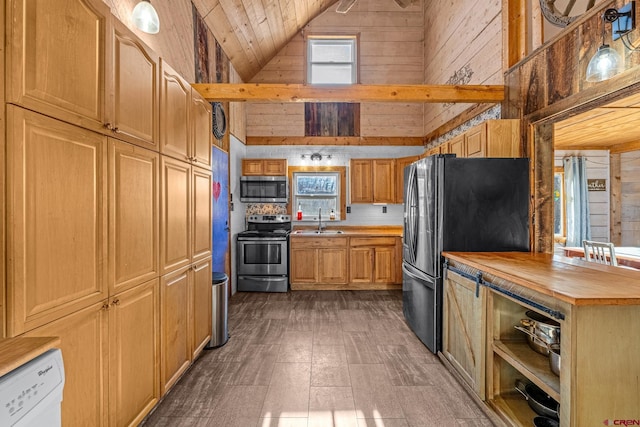 kitchen with wood walls, pendant lighting, high vaulted ceiling, and appliances with stainless steel finishes