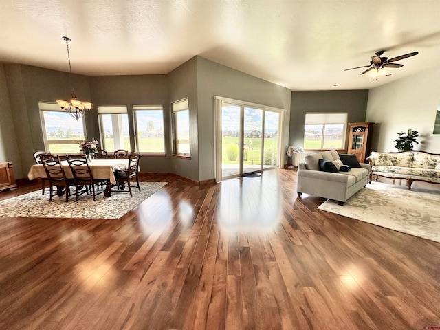 living room with ceiling fan with notable chandelier, a textured ceiling, and dark hardwood / wood-style flooring