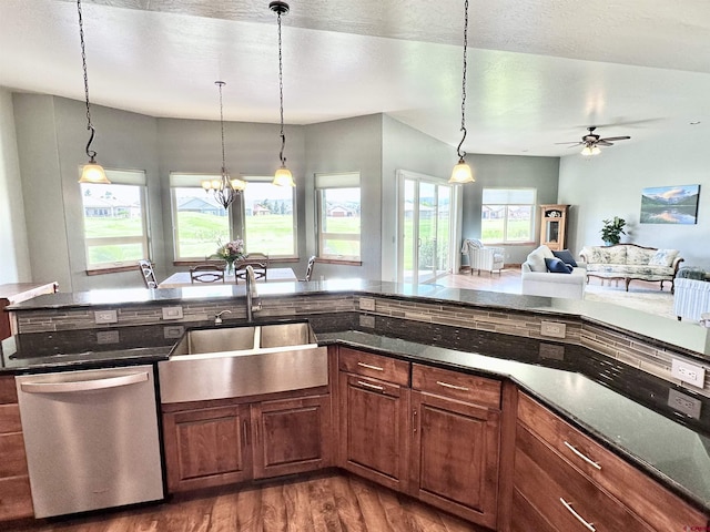 kitchen featuring dark stone countertops, sink, hanging light fixtures, dark hardwood / wood-style floors, and stainless steel dishwasher