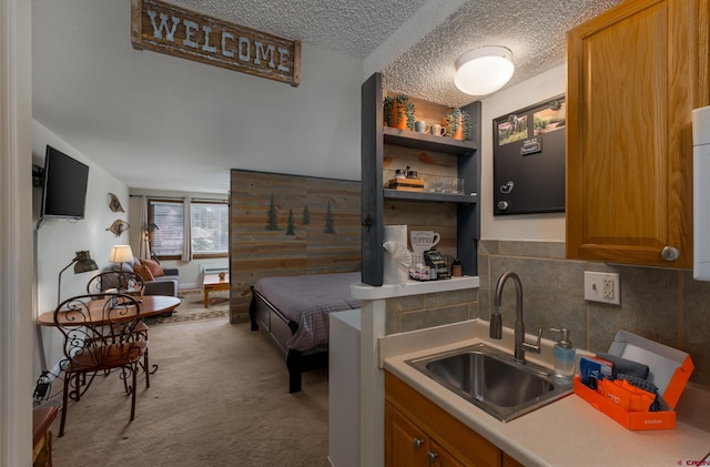 kitchen featuring sink, light colored carpet, decorative backsplash, and a textured ceiling