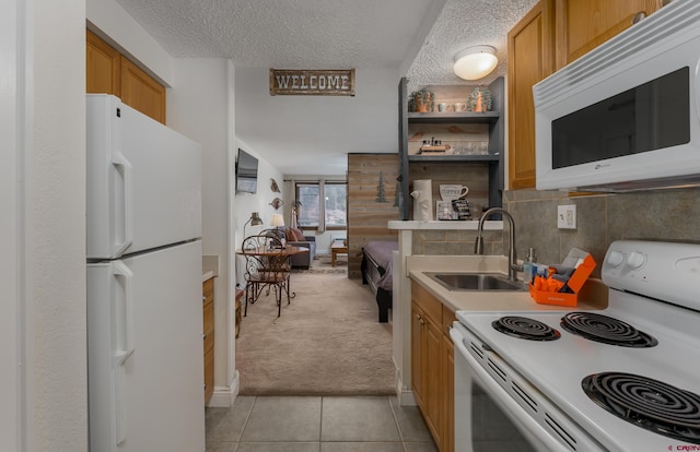 kitchen featuring light carpet, white appliances, a textured ceiling, and sink