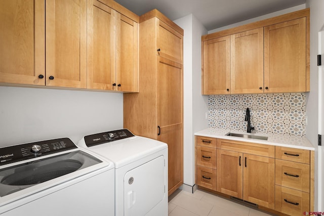 clothes washing area with cabinets, sink, light tile patterned flooring, and washing machine and clothes dryer