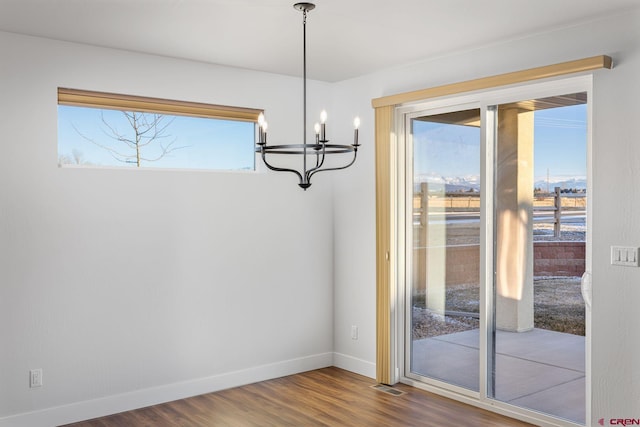 unfurnished dining area featuring hardwood / wood-style flooring and an inviting chandelier