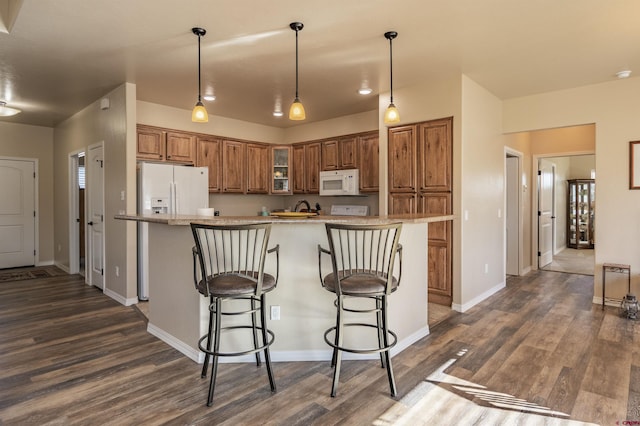 kitchen with a kitchen island, dark hardwood / wood-style floors, a kitchen bar, hanging light fixtures, and white appliances