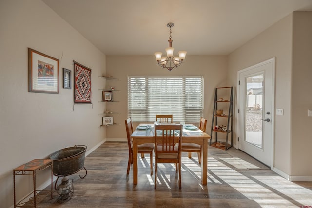 dining space with hardwood / wood-style floors and a notable chandelier