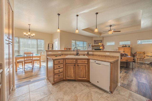 kitchen featuring pendant lighting, sink, dishwasher, a kitchen island with sink, and a tray ceiling