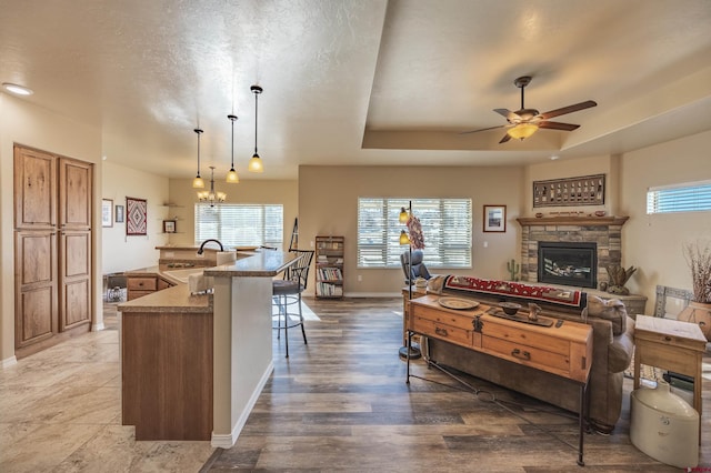 kitchen featuring sink, a breakfast bar area, a tray ceiling, an island with sink, and decorative light fixtures