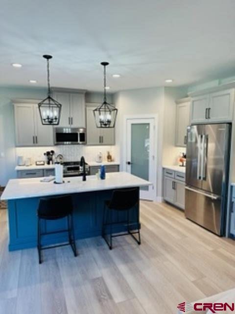 kitchen with a center island with sink, light hardwood / wood-style flooring, and stainless steel appliances