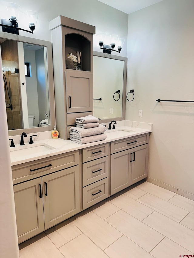 bathroom with toilet, vanity, and tile patterned flooring