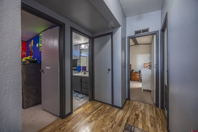 corridor featuring wood-type flooring and sink