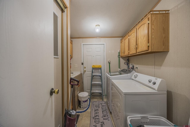 washroom featuring cabinets, ornamental molding, separate washer and dryer, and a textured ceiling