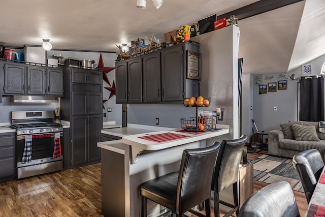 kitchen with dark hardwood / wood-style flooring, gas range, a kitchen breakfast bar, and kitchen peninsula