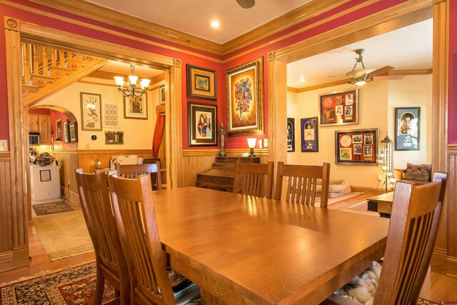 dining space with ceiling fan with notable chandelier, light hardwood / wood-style flooring, and ornamental molding