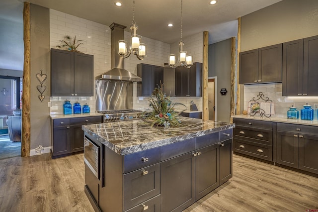 kitchen featuring pendant lighting, light hardwood / wood-style flooring, dark brown cabinetry, a kitchen island, and decorative backsplash