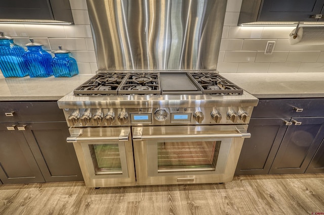 kitchen featuring dark brown cabinetry, light hardwood / wood-style flooring, range with two ovens, and backsplash