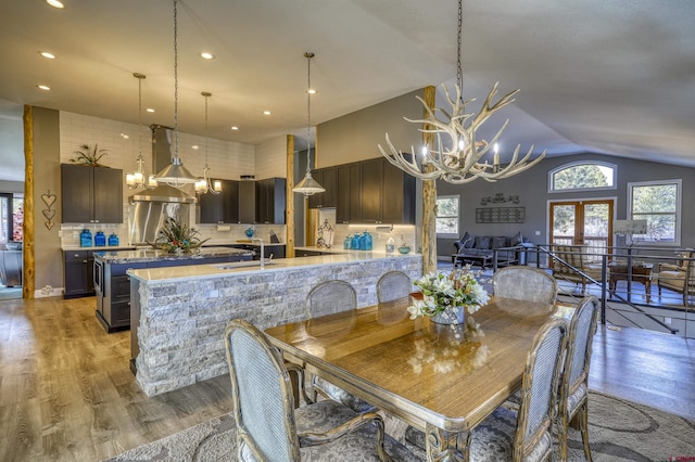 dining space featuring lofted ceiling, sink, a chandelier, light hardwood / wood-style floors, and french doors