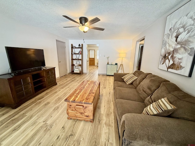 living room with ceiling fan, light hardwood / wood-style floors, and a textured ceiling