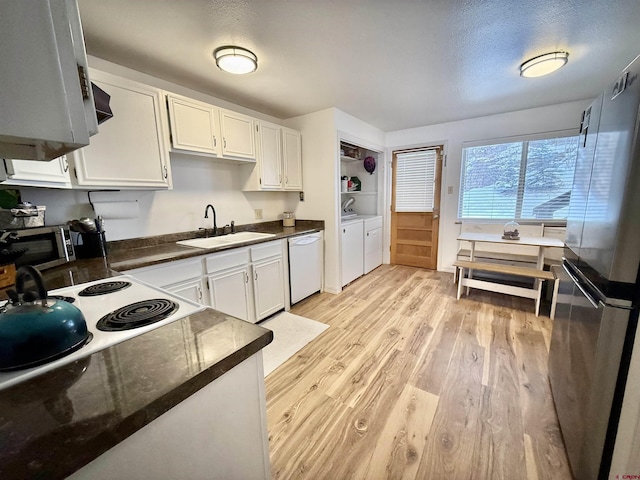 kitchen with sink, washer and dryer, stainless steel refrigerator, white dishwasher, and white cabinets