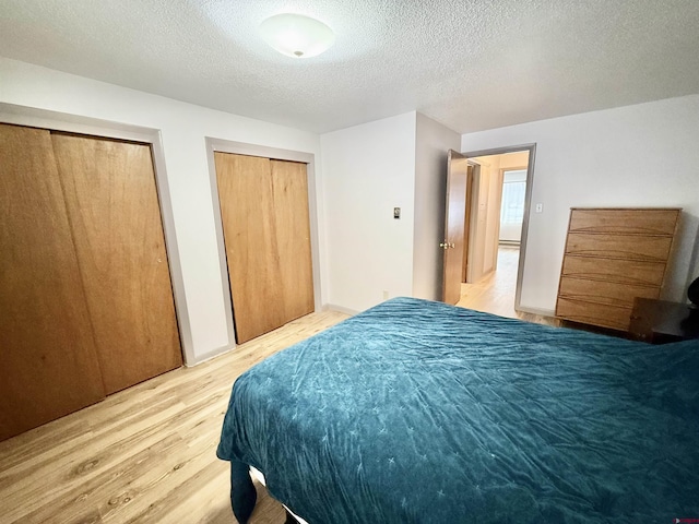 bedroom featuring multiple closets, hardwood / wood-style floors, and a textured ceiling