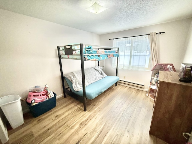 bedroom featuring light hardwood / wood-style floors, a textured ceiling, and baseboard heating