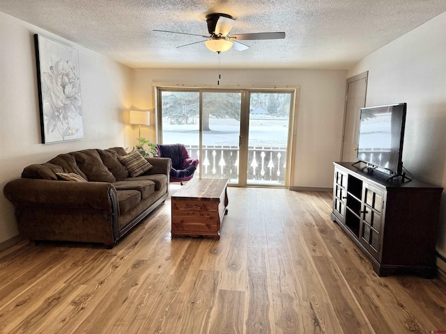 living room featuring ceiling fan, light hardwood / wood-style flooring, and a textured ceiling