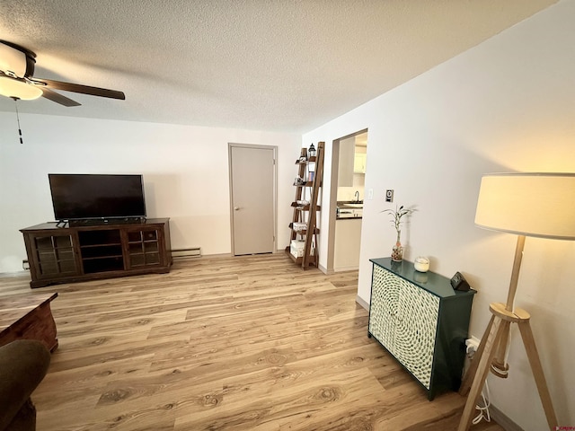 living room with a baseboard radiator, a textured ceiling, and light wood-type flooring