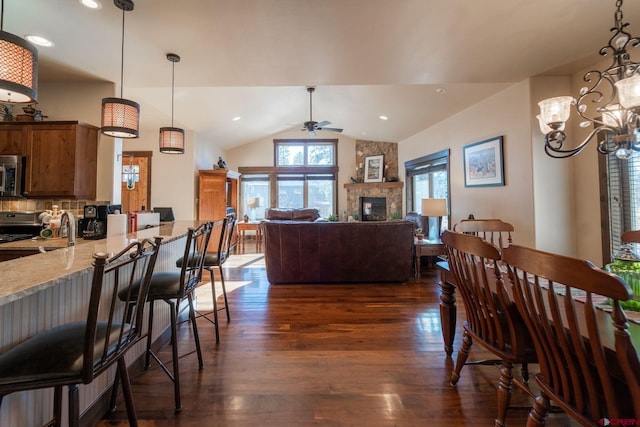 kitchen with tasteful backsplash, a large fireplace, dark hardwood / wood-style floors, pendant lighting, and light stone countertops