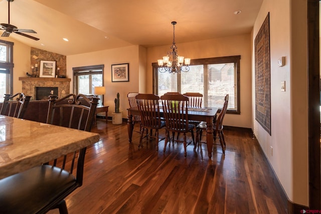 dining space with dark hardwood / wood-style floors, a healthy amount of sunlight, a fireplace, and vaulted ceiling