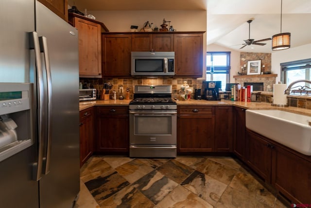 kitchen featuring lofted ceiling, sink, appliances with stainless steel finishes, a fireplace, and decorative backsplash