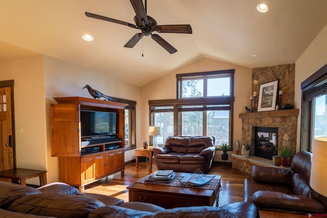 living room with vaulted ceiling, a stone fireplace, ceiling fan, and light hardwood / wood-style floors