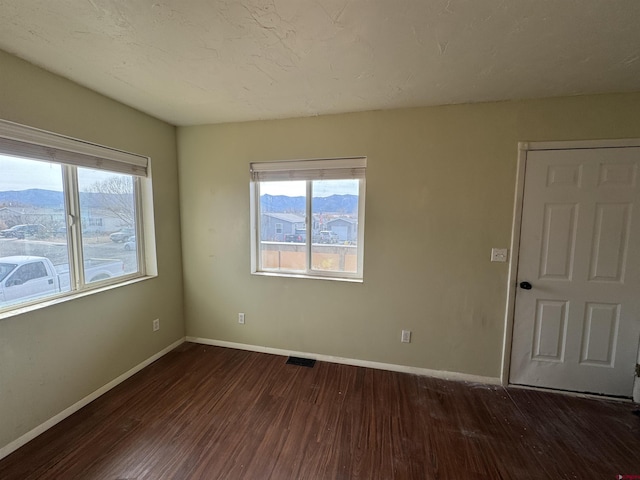 unfurnished room with a mountain view and dark hardwood / wood-style flooring