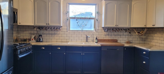 kitchen with sink, backsplash, white cabinets, and appliances with stainless steel finishes