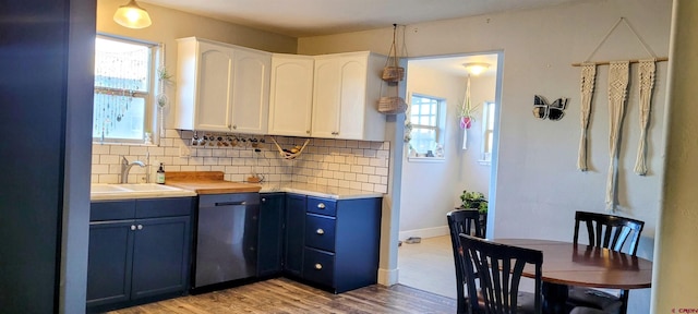 kitchen with sink, dishwasher, light hardwood / wood-style floors, white cabinets, and decorative backsplash