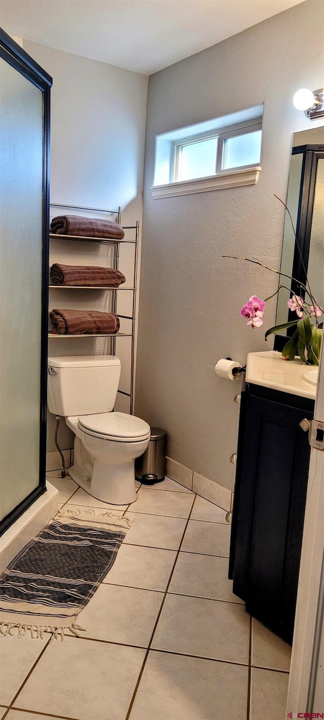 bathroom with walk in shower, vanity, toilet, and tile patterned flooring