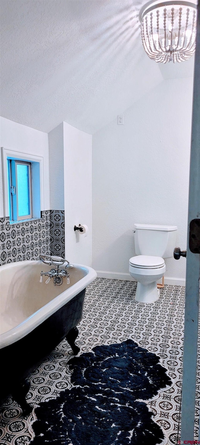 bathroom with a tub to relax in, a textured ceiling, and toilet