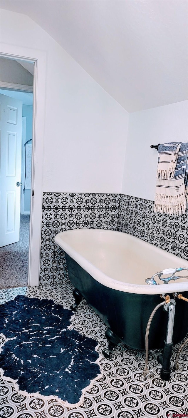 bathroom with lofted ceiling and a tub to relax in