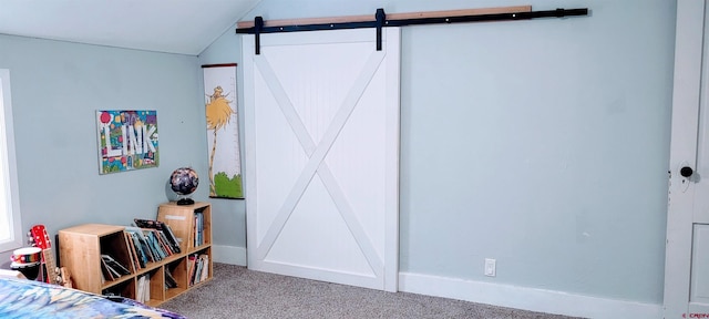 bedroom with a barn door, carpet flooring, and lofted ceiling