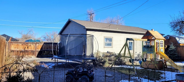 back of house featuring a trampoline and a playground