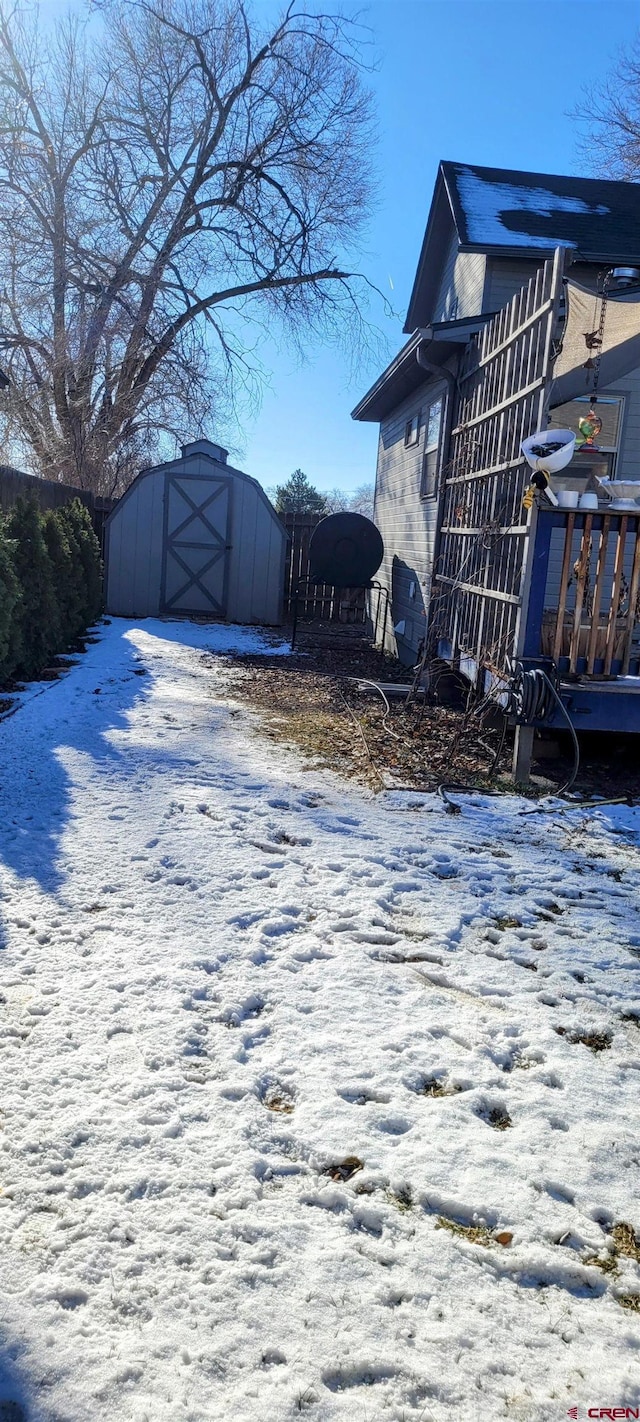 yard covered in snow featuring a storage shed