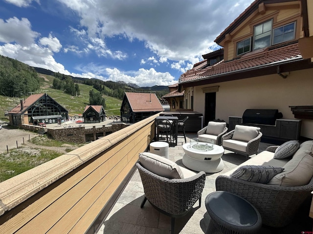 view of patio / terrace featuring a grill, a mountain view, a balcony, and an outdoor fire pit