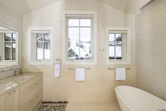 bathroom featuring vaulted ceiling, a healthy amount of sunlight, tile walls, and a tub to relax in